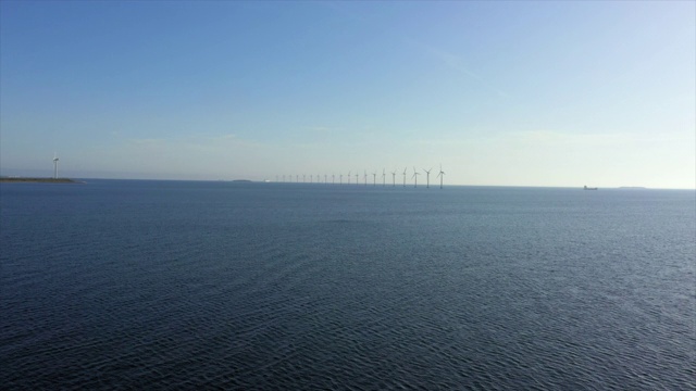 航拍的风力涡轮机在海上对着蓝天，无人机向前飞向地平线在晴朗的一天-哥本哈根，丹麦视频素材
