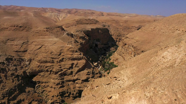空中拍摄的岩石峡谷对天空晴朗的一天，无人机向前飞行的自然景观-死海，以色列视频素材