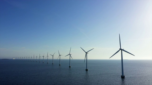 晴天里，空中封锁拍摄的蓝天下的海上风力涡轮机，无人机在水面上飞行——丹麦哥本哈根视频素材