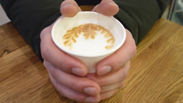 一个男人用热咖啡暖手。视频下载