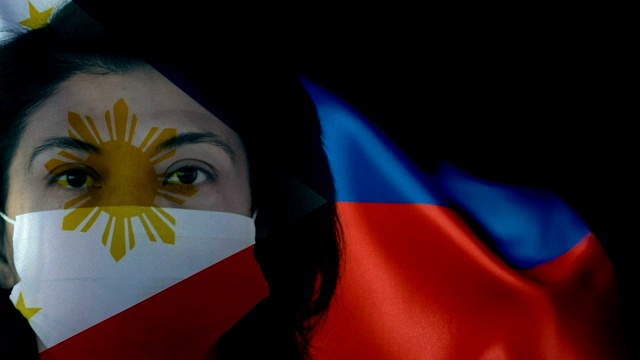菲律宾国旗上戴着防护面罩的妇女。保护病毒和感染。视频下载