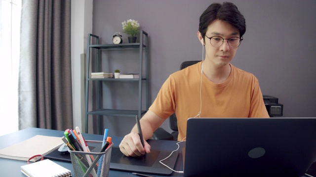 迷人的亚洲男人用笔记本电脑修图。在家工作概念，或在隔离期间远程工作视频下载