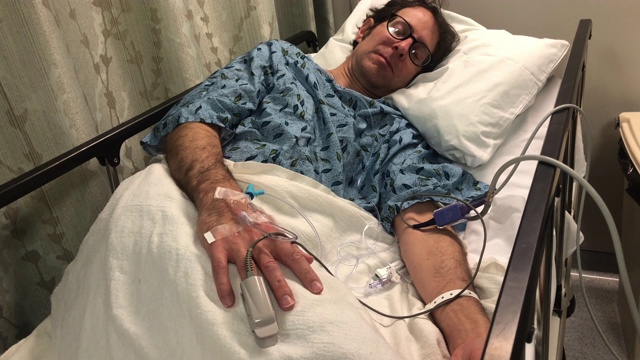 一名男子躺在医院的病床上，手上插着静脉导管视频素材