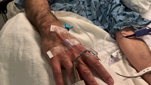 一个男人的手的特写与静脉导管和脉搏血氧计在他的手指视频素材