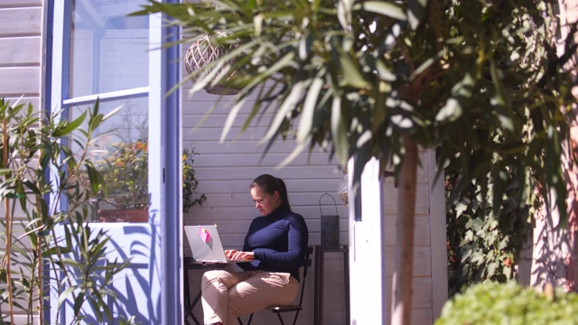 在花园里用笔记本电脑工作的女人。视频素材