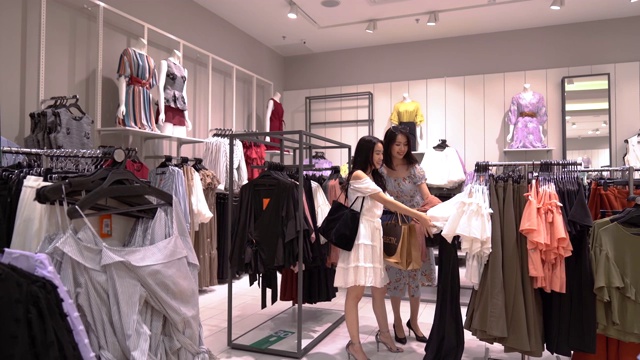亚洲华人女性在服装零售店购物和浏览视频素材