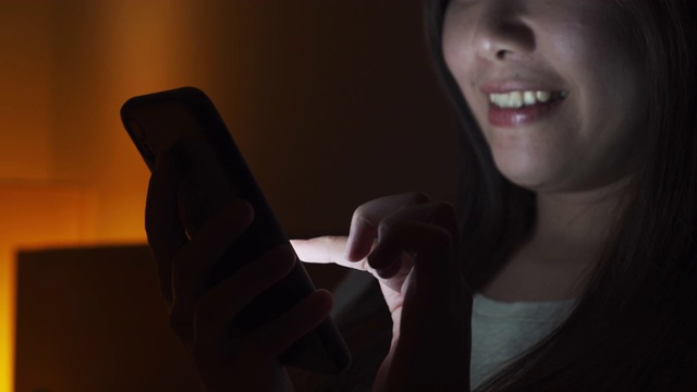 晚上在床上玩智能手机的亚洲女人视频素材