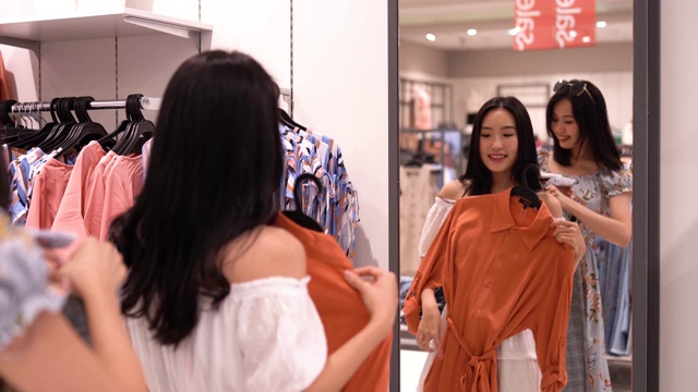 亚洲华人女性在服装零售店购物和浏览视频下载