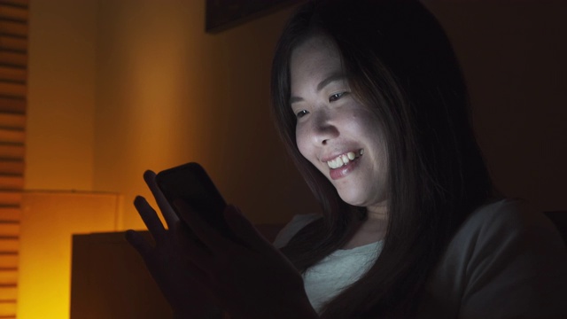 晚上在床上玩智能手机的亚洲女人视频素材