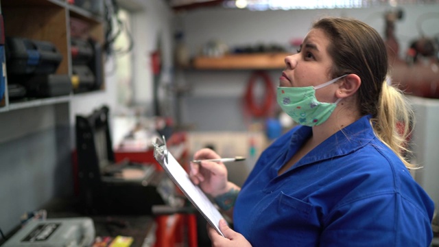 肖像的汽车技工妇女做检查清单在汽车修理店视频素材