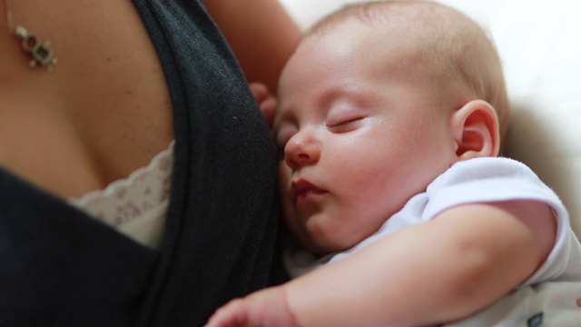 刚出生的婴儿闭着眼睛睡在妈妈的怀里视频素材