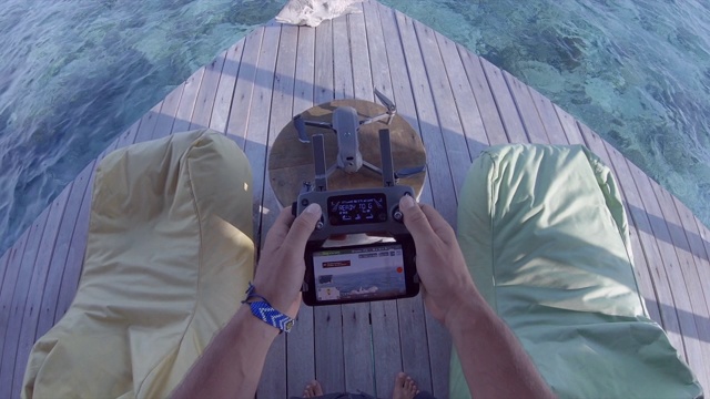 一名男子在一个岛屿度假酒店使用遥控和智能手机驾驶无人机进行航拍。视频下载