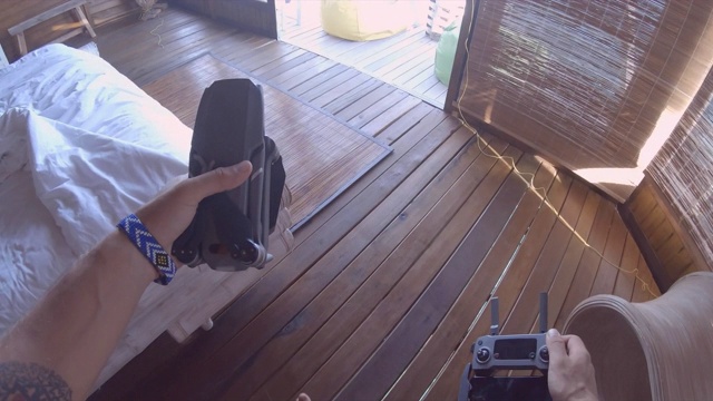 一名男子在一个岛屿度假酒店使用遥控和智能手机驾驶无人机进行航拍。视频素材