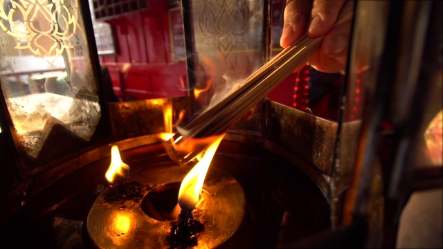 在庙里举行仪式时，手捧香入火的特写。手里烧着香。视频购买