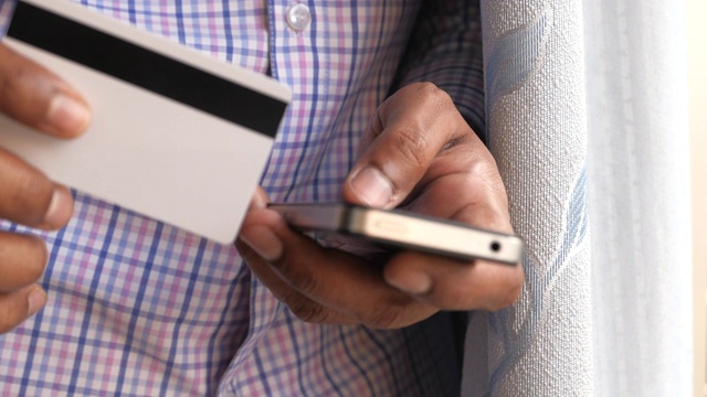 一名男子手持信用卡用智能手机进行网上购物视频素材