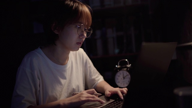 年轻的亚洲女性在晚上在家工作视频下载