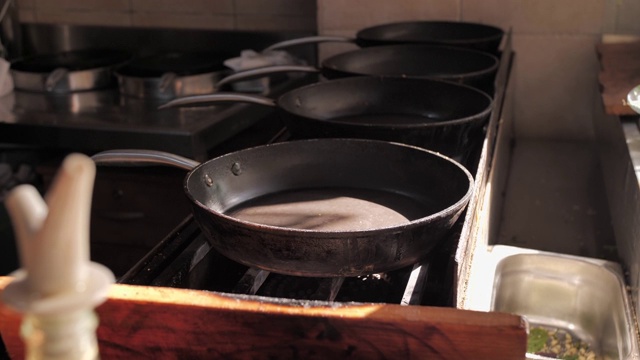 在餐厅厨房的煤气炉上清空煎锅。阳光下舒适明亮的厨房内部。近距离视频下载