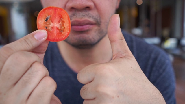 成熟的商人吃西红柿，竖起大拇指表示身体状况良好视频素材