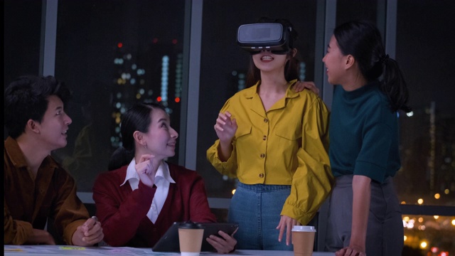 亚洲用户体验开发人员和ui设计师在夜晚的城市灯光下，在现代办公室中使用手机应用原型设计虚拟现实眼镜。创意数字发展机构。移出视频素材