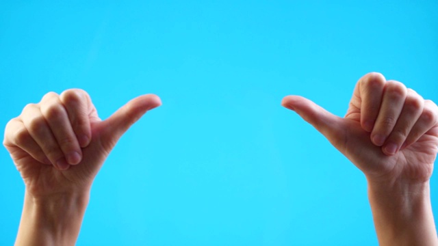 女人的手指向copyspace，并在蓝色背景上竖起大拇指视频下载