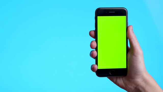 一位女士手持一部蓝色背景、绿色屏幕的智能手机。只有手的特写镜头视频下载