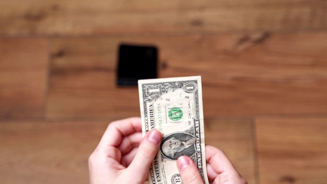 女人从钱包里拿出一美元，手的特写视频下载