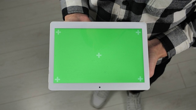 一名男子站在办公室里，手里拿着带有绿色屏幕色度键的数字平板电脑视频下载