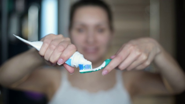 女孩往牙刷上挤了一点牙膏，开始刷牙视频素材