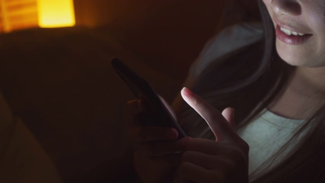 近距离的亚洲妇女使用智能手机在床上晚上视频素材