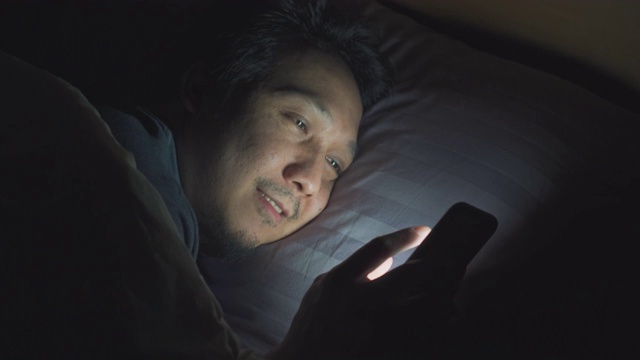 亚洲男人晚上在床上玩智能手机视频下载