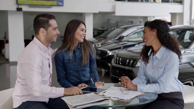 一对可爱的拉丁美洲夫妇在汽车经销商与友好的黑人女销售员签订了一份合同视频素材