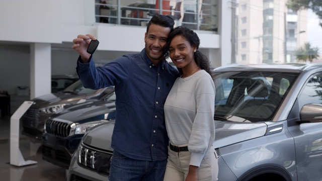 幸福的不同的夫妇在经销商买了一辆车，并拿着钥匙，面对镜头微笑视频素材