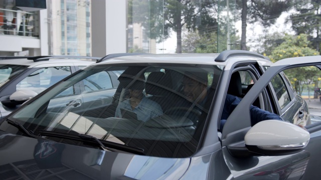 一个拉丁美洲男子在一家汽车经销店与一位漂亮的女售货员一起看一辆他喜欢的汽车的内部视频素材