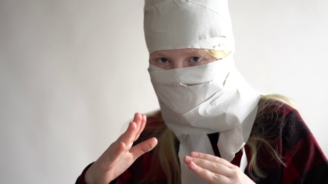 搞笑视频-由于冠状病毒的流行而被隔离。戴着卫生纸面具的女孩在灰色背景下摆姿势。视频下载