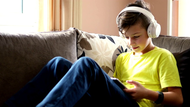 带耳机的孩子在家里使用数字平板电脑视频素材