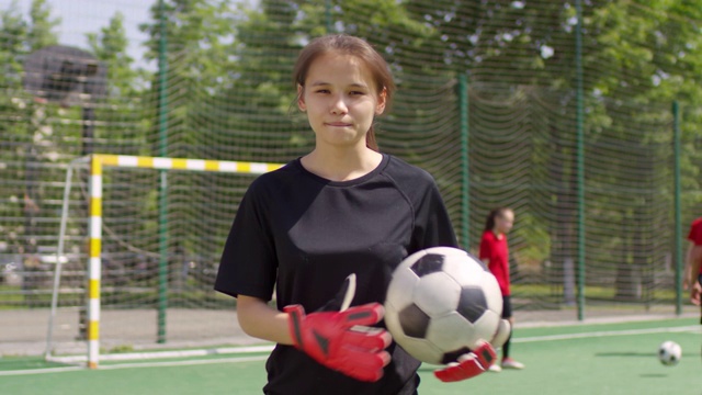 年轻女守门员的肖像与足球站在球场上视频素材