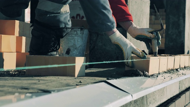 一个工人正在新水泥上铺砖。建筑工地的建筑工人。视频素材