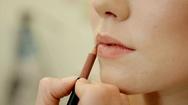 一个专业化妆师应用口红的模特的嘴唇在美容时尚行业的特写镜头视频素材
