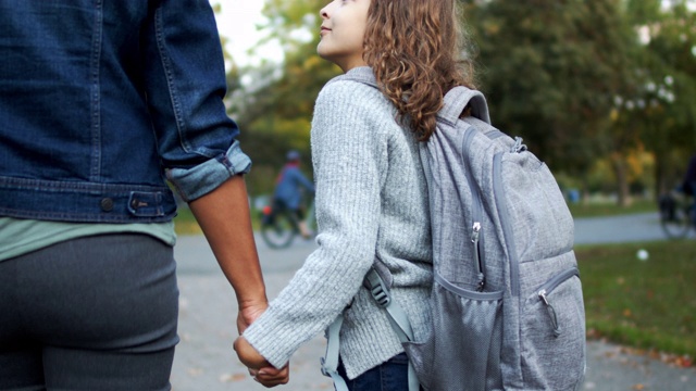 小学女孩牵着妈妈的手从学校走回家视频素材