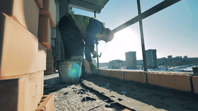 建筑工人正在新混凝土上砌砖。建筑工地的建筑工人。视频素材