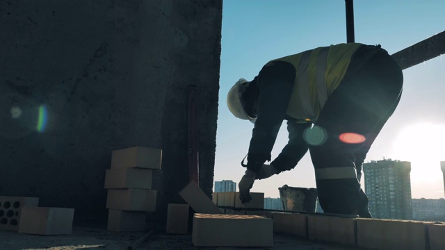 建筑工人正在一座多层建筑里砌砖并修理。建筑工地的建筑工人。视频素材