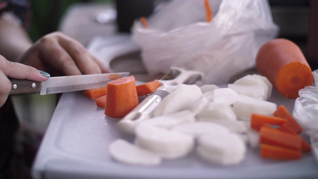 人的手用菜刀切生胡萝卜。视频素材