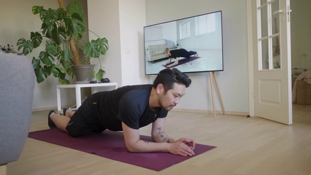 日本男子在家在线健身时坚持平板支撑视频素材