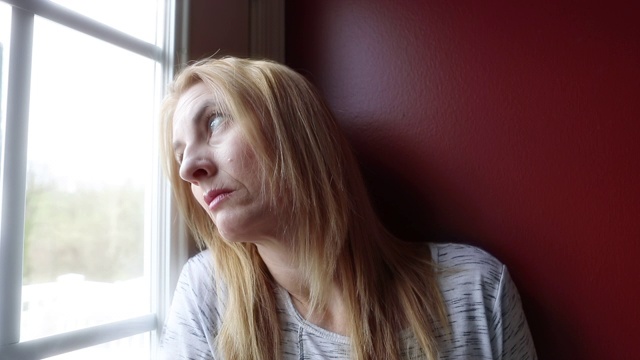 沮丧的中年妇女向窗外看视频素材