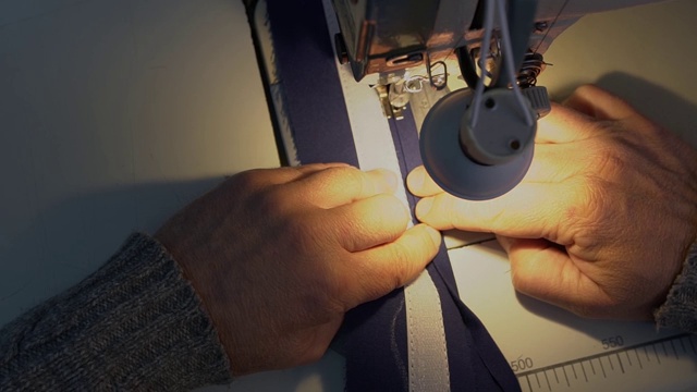 一个男人在缝纫机上缝游艇配件。特写镜头视频下载