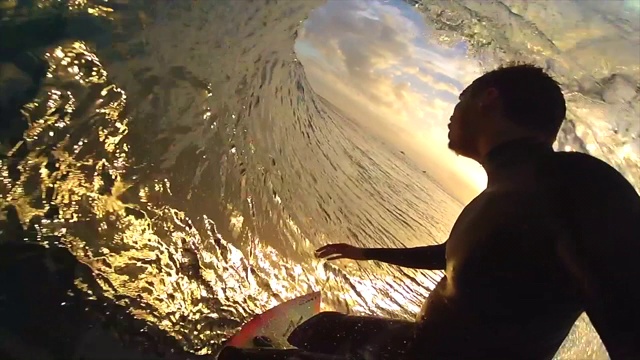 一个冲浪者在冲浪板上冲浪和太阳与日落的剪影的观点。——慢动作视频素材