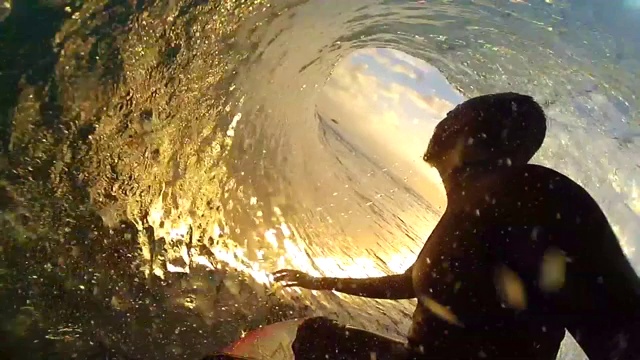 一个冲浪者在冲浪板上冲浪和太阳与日落的剪影的观点。——慢动作视频下载