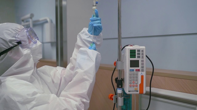 一名医务人员在医院为一名身着防护服的患者检查COVID-19视频下载