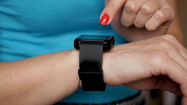 一名女性正在使用她的智能手表触摸屏可穿戴技术设备。女孩在可穿戴智能手表电脑设备上做手势，特写。视频素材