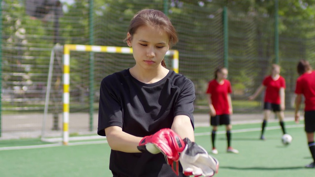年轻女子足球运动员戴上守门员手套视频素材